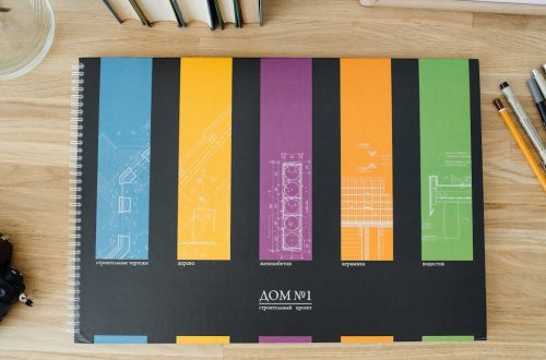 Design and architecture workbook with colorful blueprints on a wooden desk.